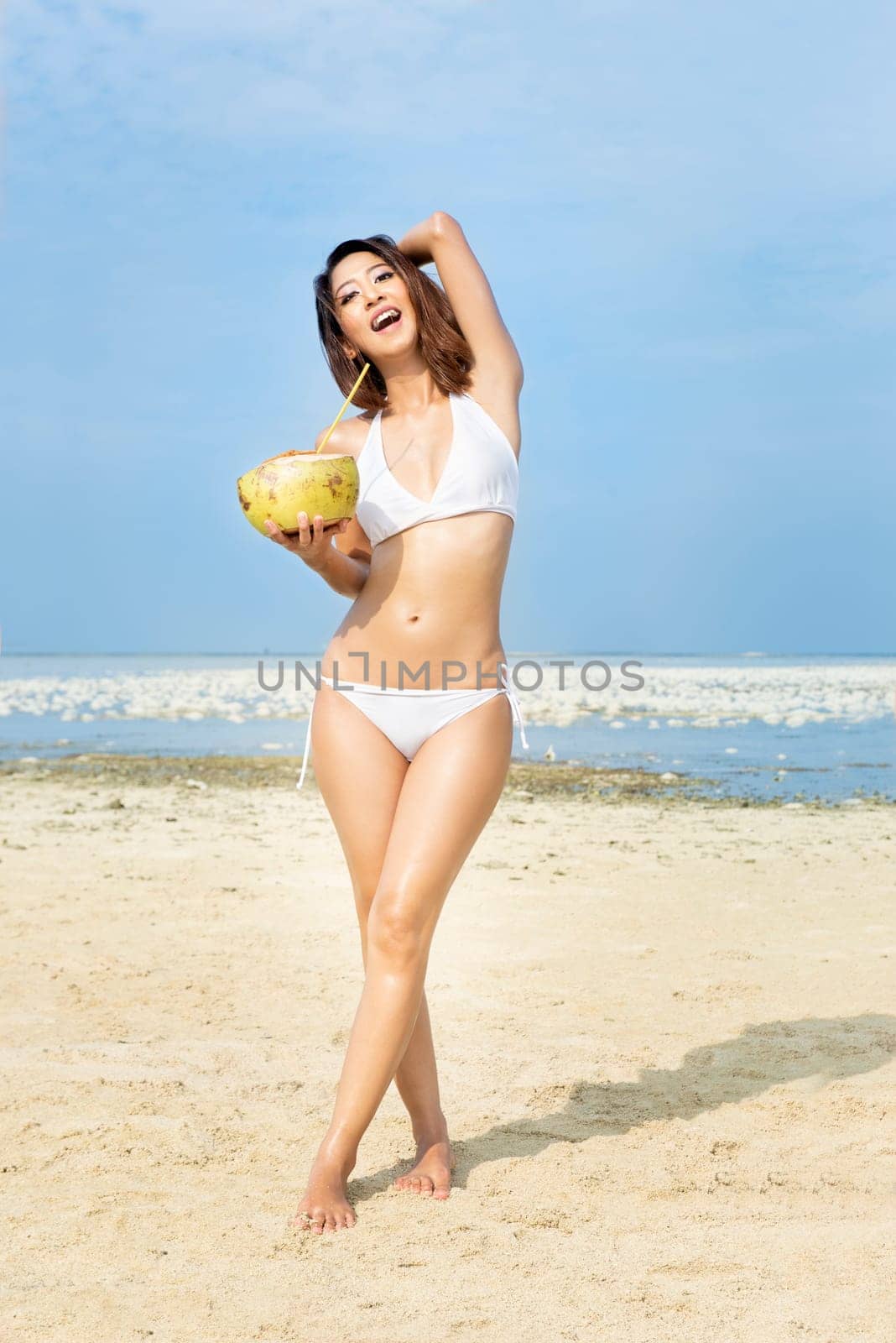 Asian sexy girl in bikini holding coconuts on the beach. Summer vacation