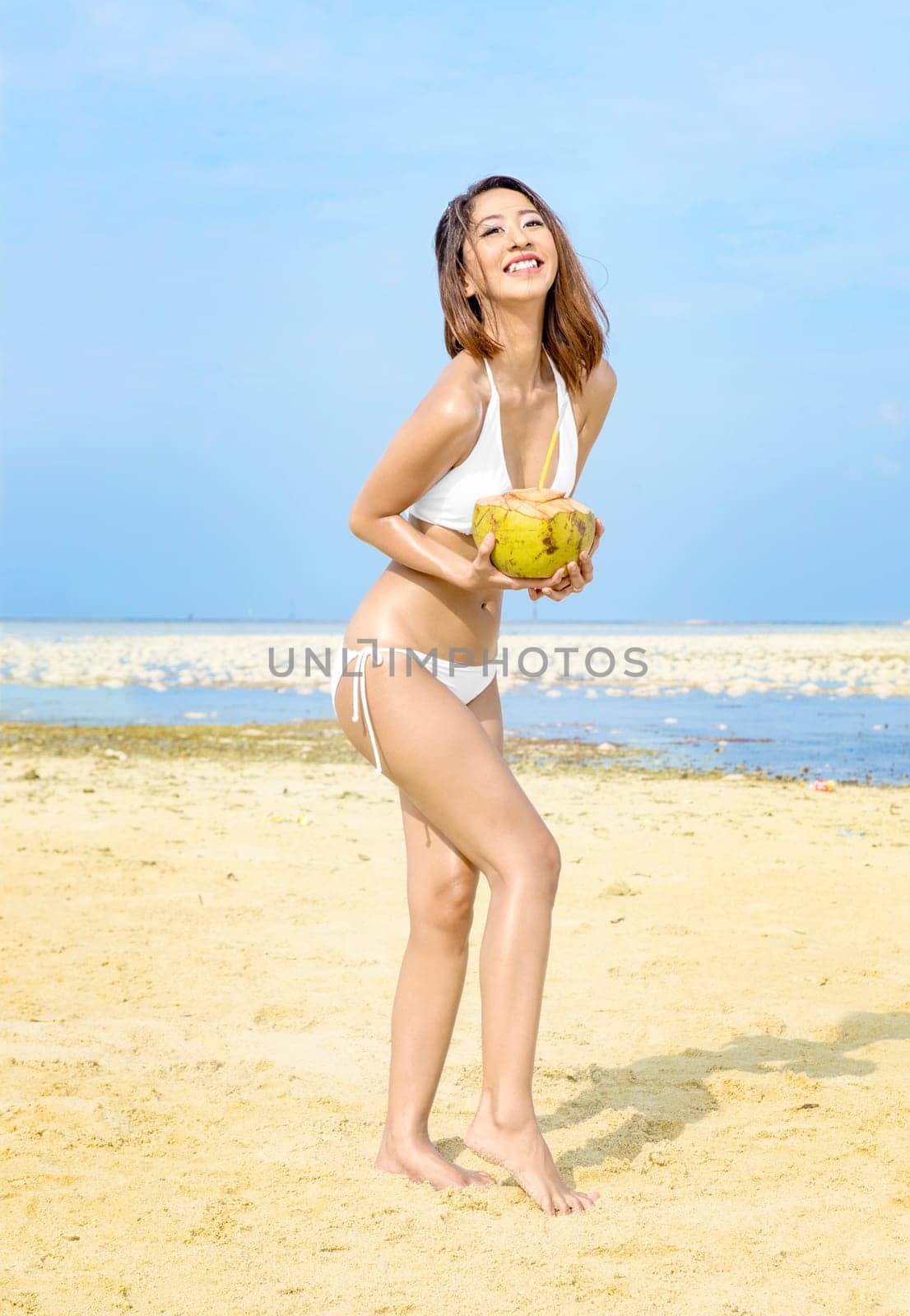 Asian sexy girl in bikini holding coconuts on the beach. Summer vacation
