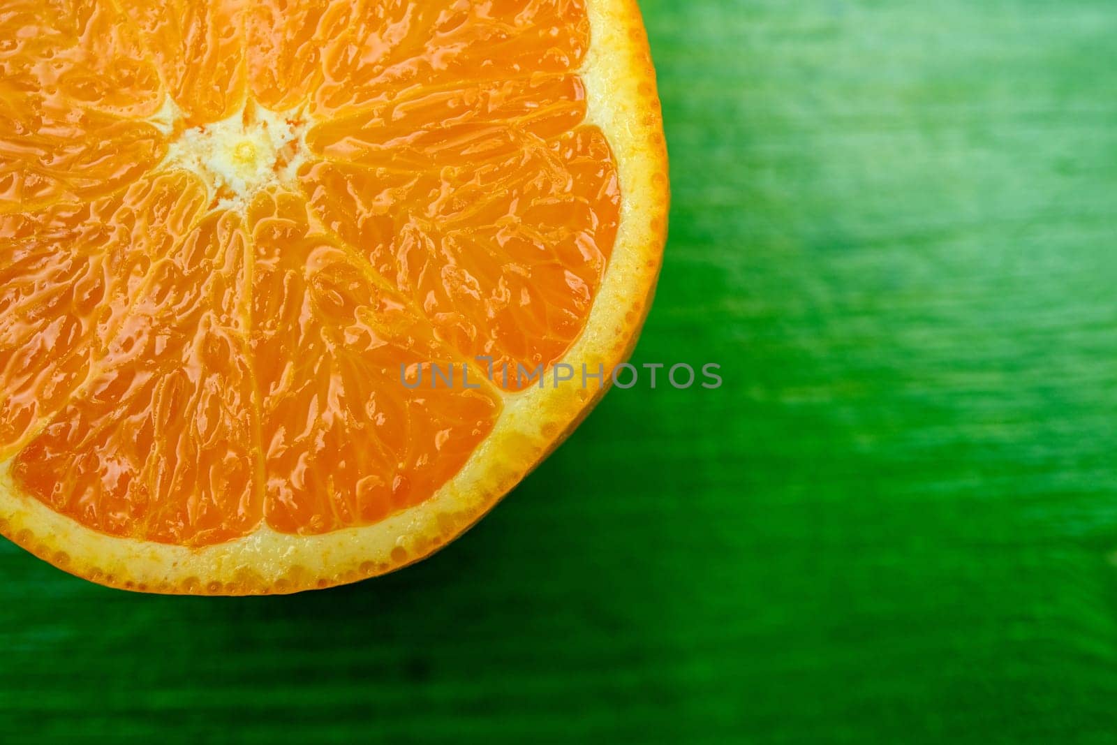 closeup of a half ripe juicy orange on green ground