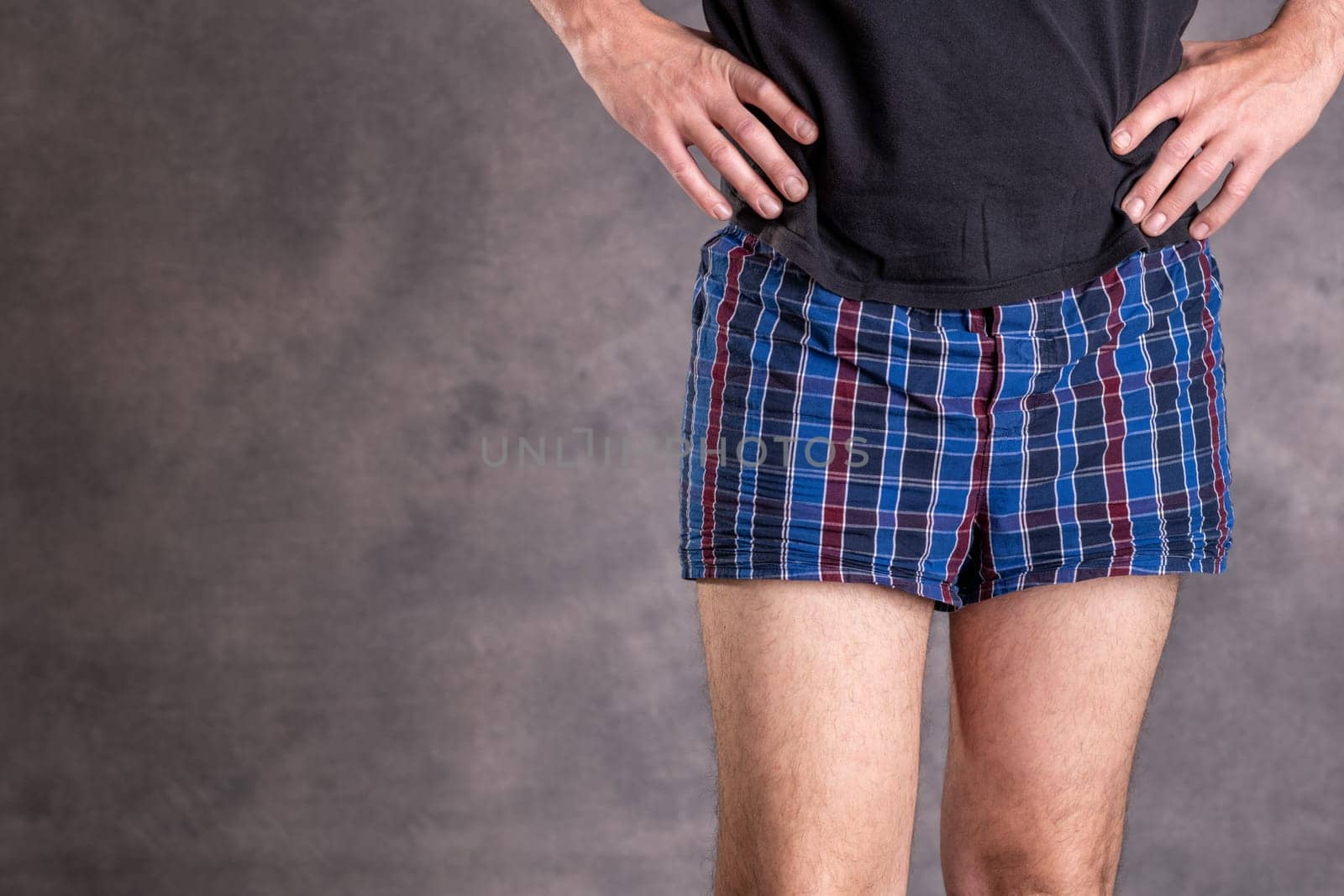 man in blue plaid boxer shorts in front of gray background