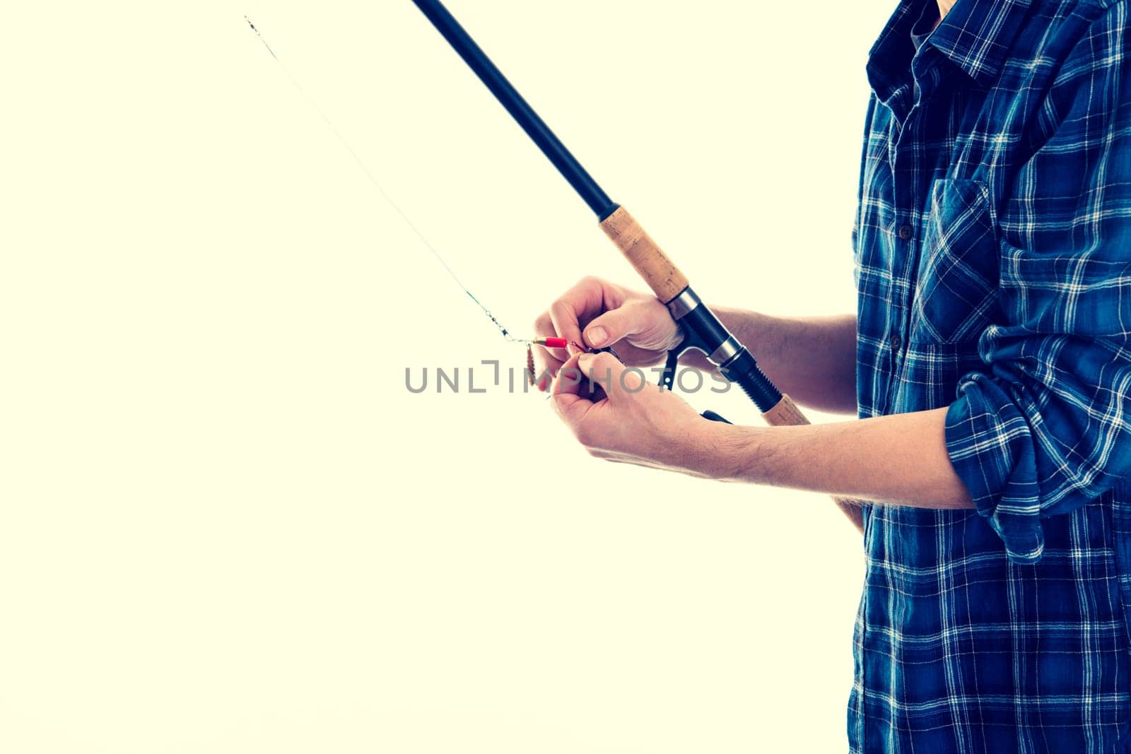 man with fishing rod and blue plaid shirt in front of white background