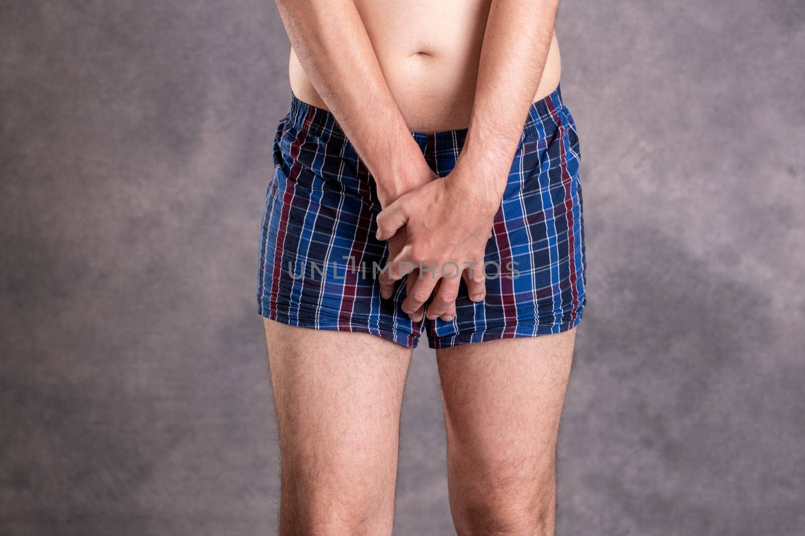 man in blue plaid boxer shorts in front of gray background