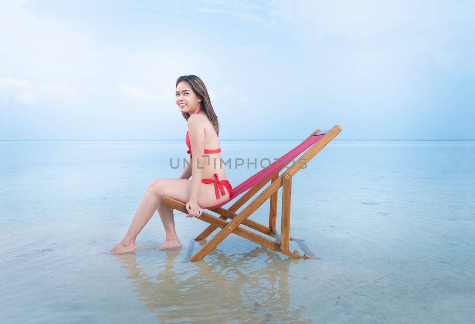 Asian sexy girl in bikini sitting on the beach chair at seaside. Summer vacation