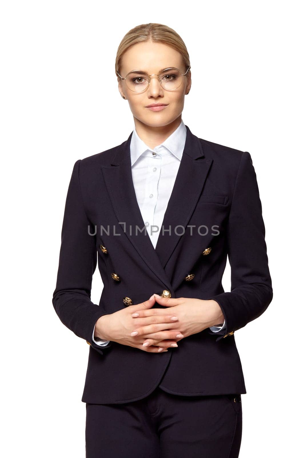 Studio portrait of pretty blonde in business outfit stands with folded hands.