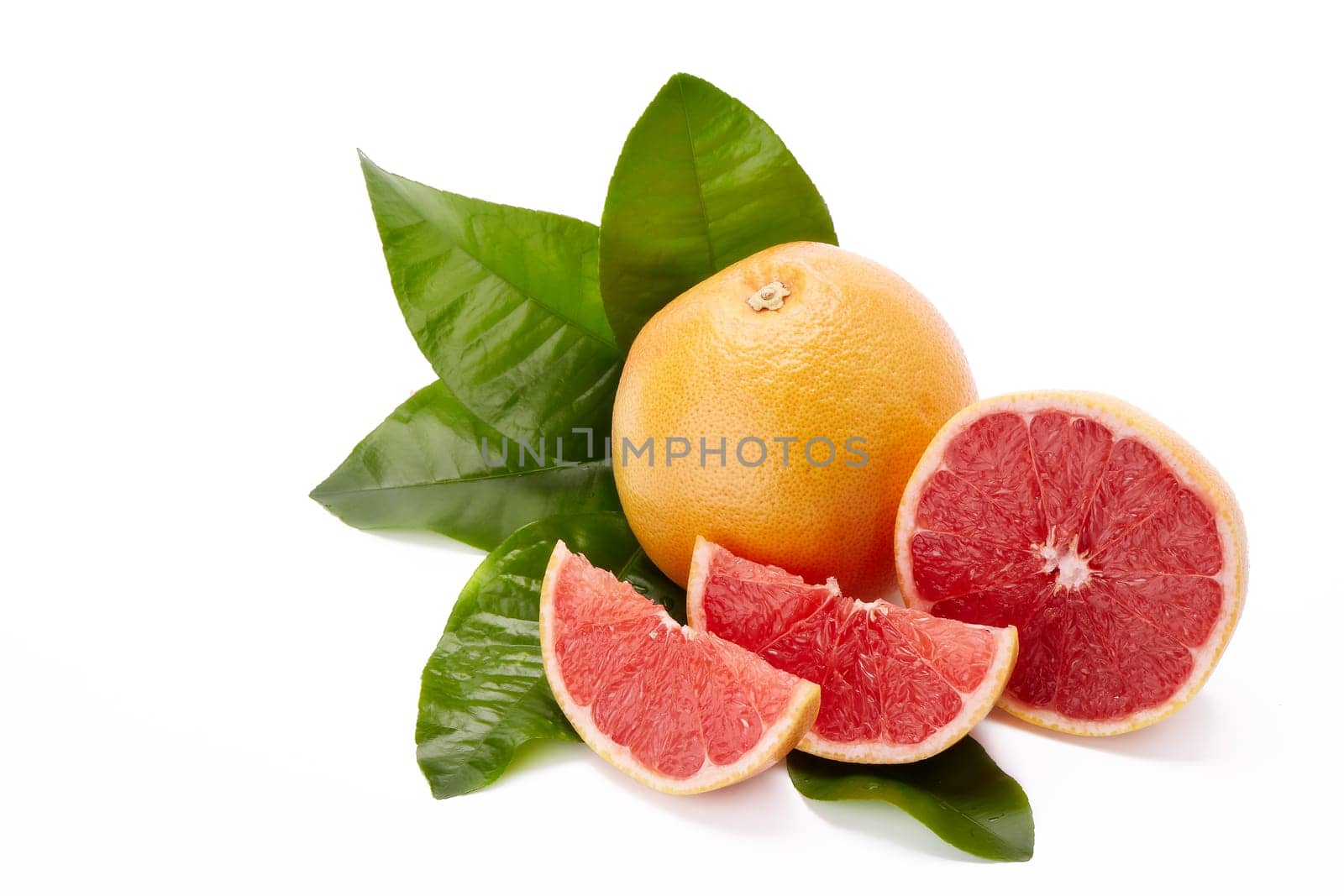Fresh juicy whole grapefruit with green leaves and appetizing slices of ripe grapefruit on a white background.