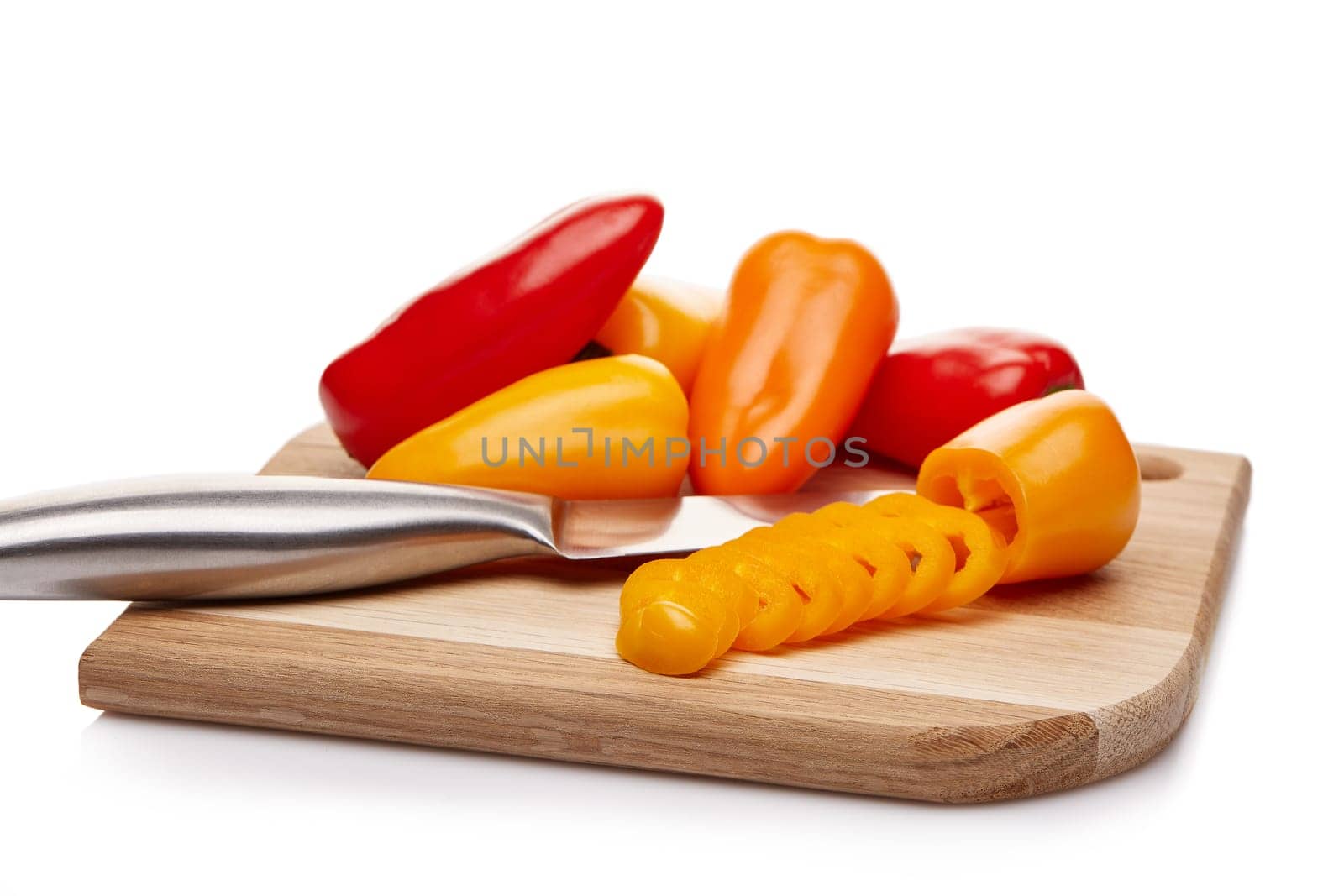Fresh ripe peppers lying on wooden cutting board on a white background.