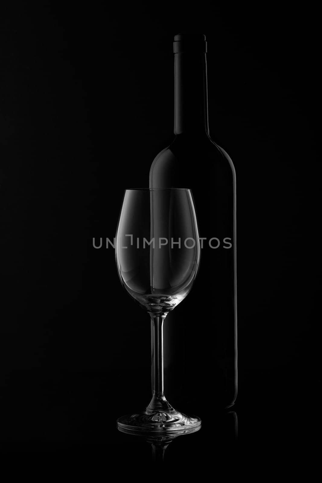Silhouette of wine bottle and empty wineglass on a black background with reflection. Contour with gradient and highlights
