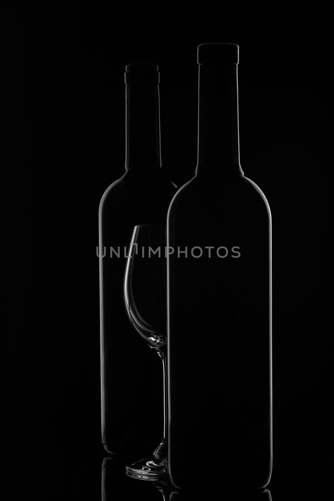 Silhouette of two wine bottles and empty wineglass on a black background with reflection. Contour with gradient and highlights