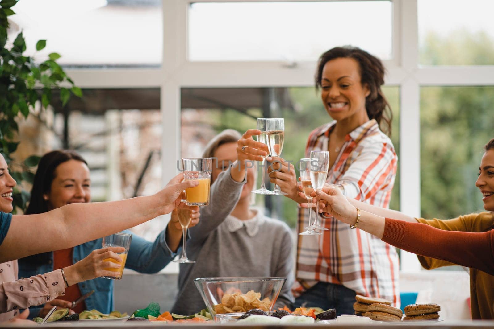 Small group of female friends preparing a healthy lunch inside of a conservatory on a weekend away.