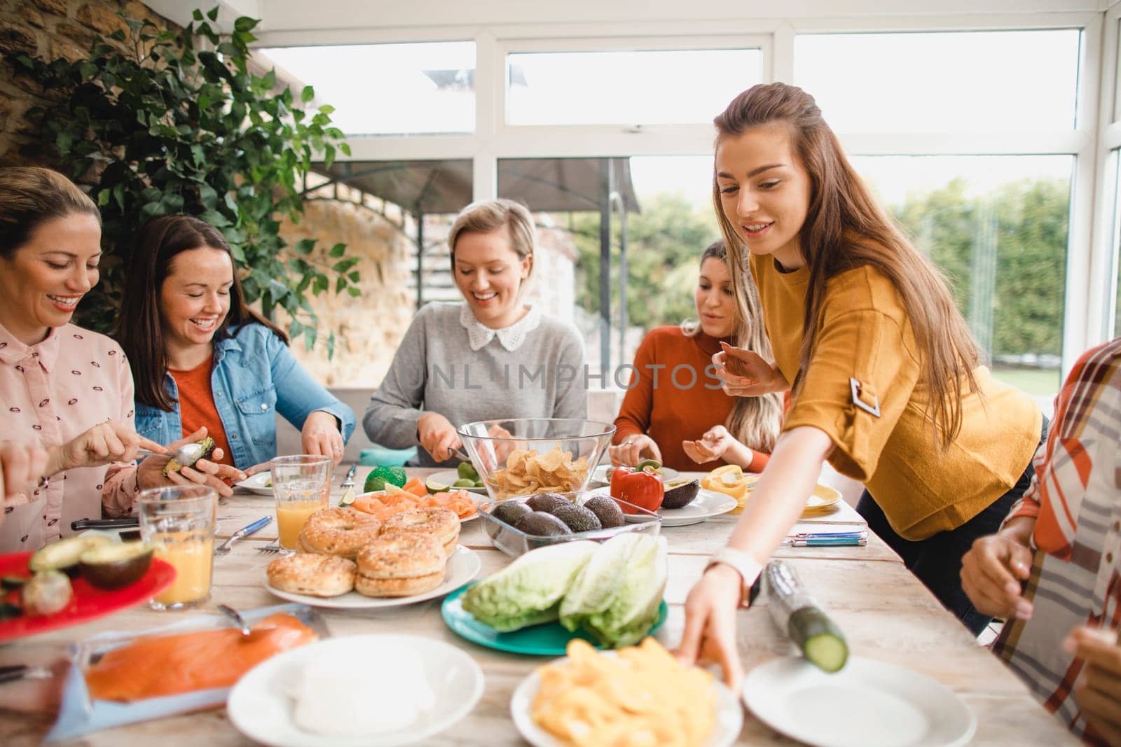 Small group of female friends preparing a healthy lunch inside of a conservatory on a weekend away.