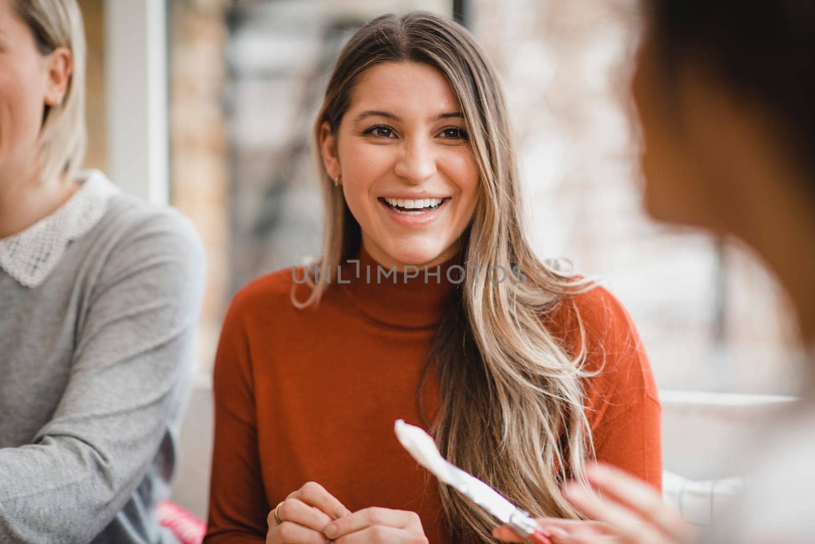 Portrait of a young female adult sitting indoors. She is talking to a friend while making her lunch.