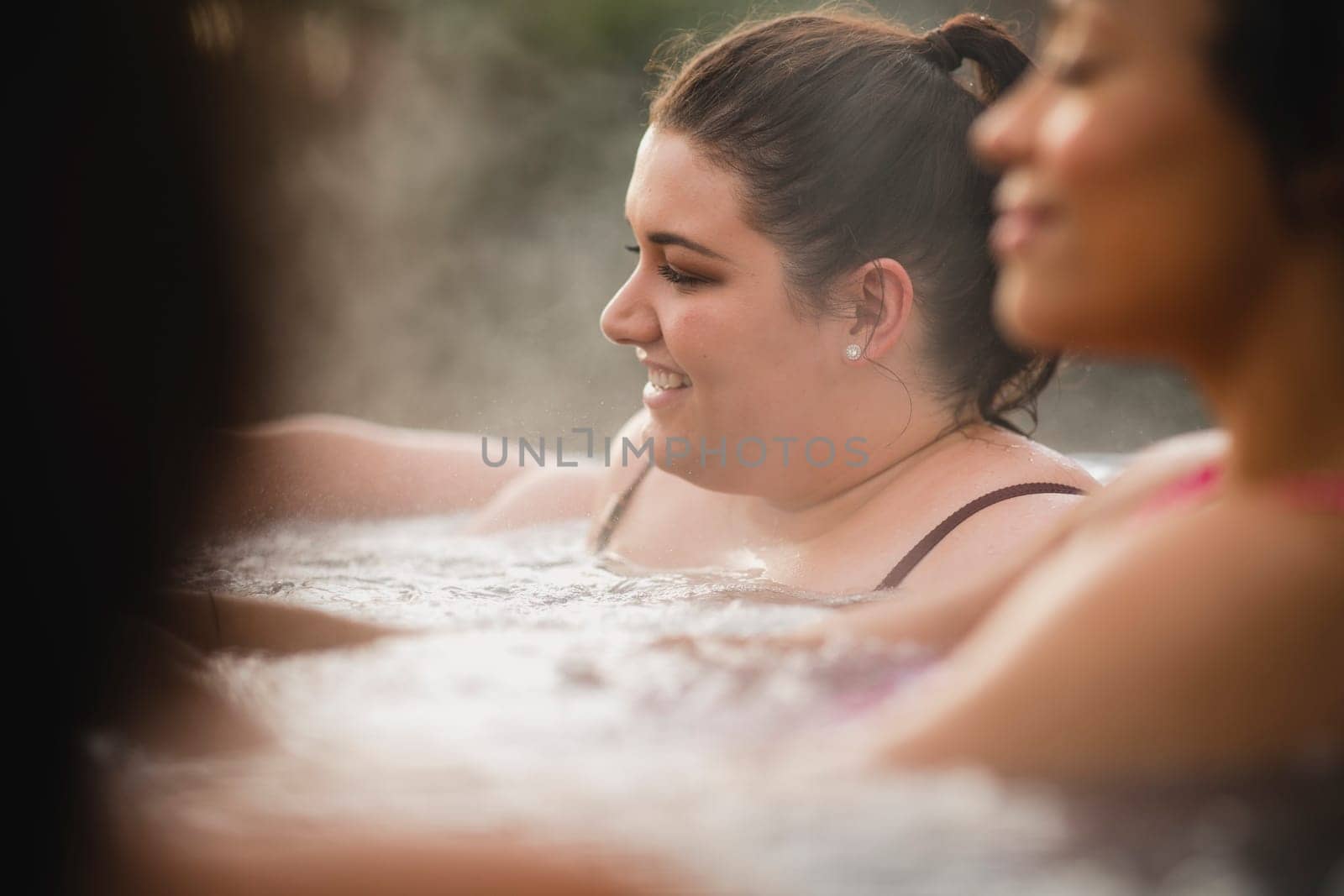 Mid adult woman relaxing in a hot tub with her friends.