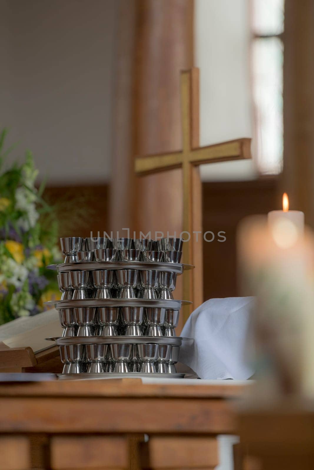 Church cross stands on an evangelical altar with a communion cup and blurred burning candle
