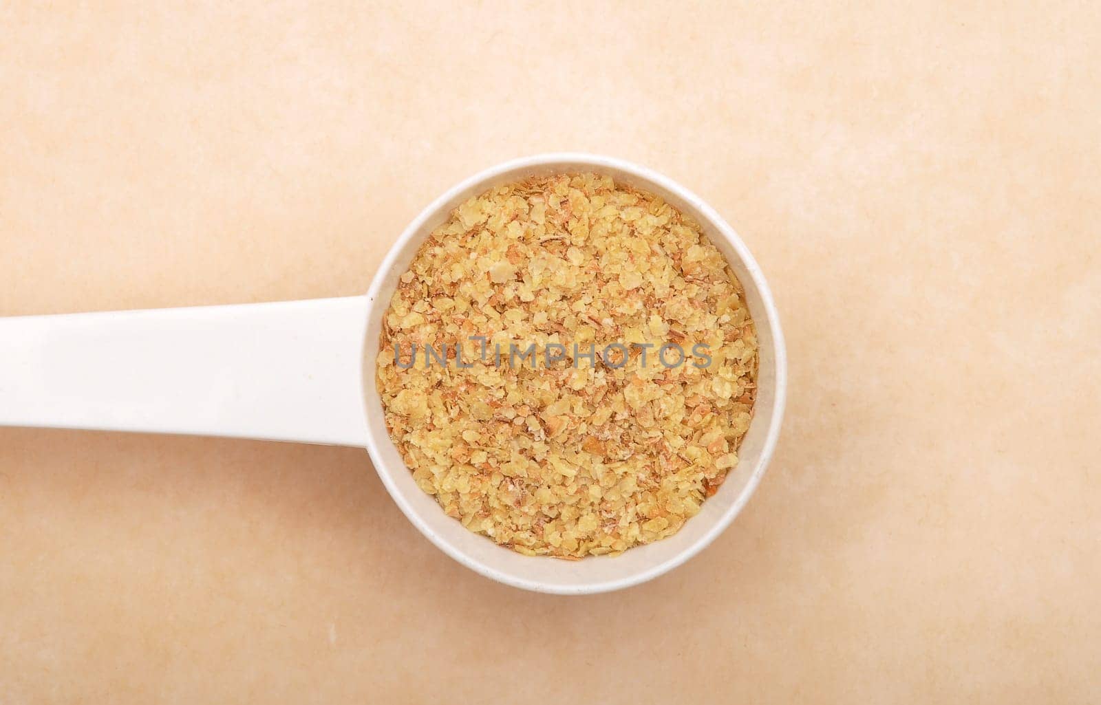 Wheat germs in measuring spoon on brown background