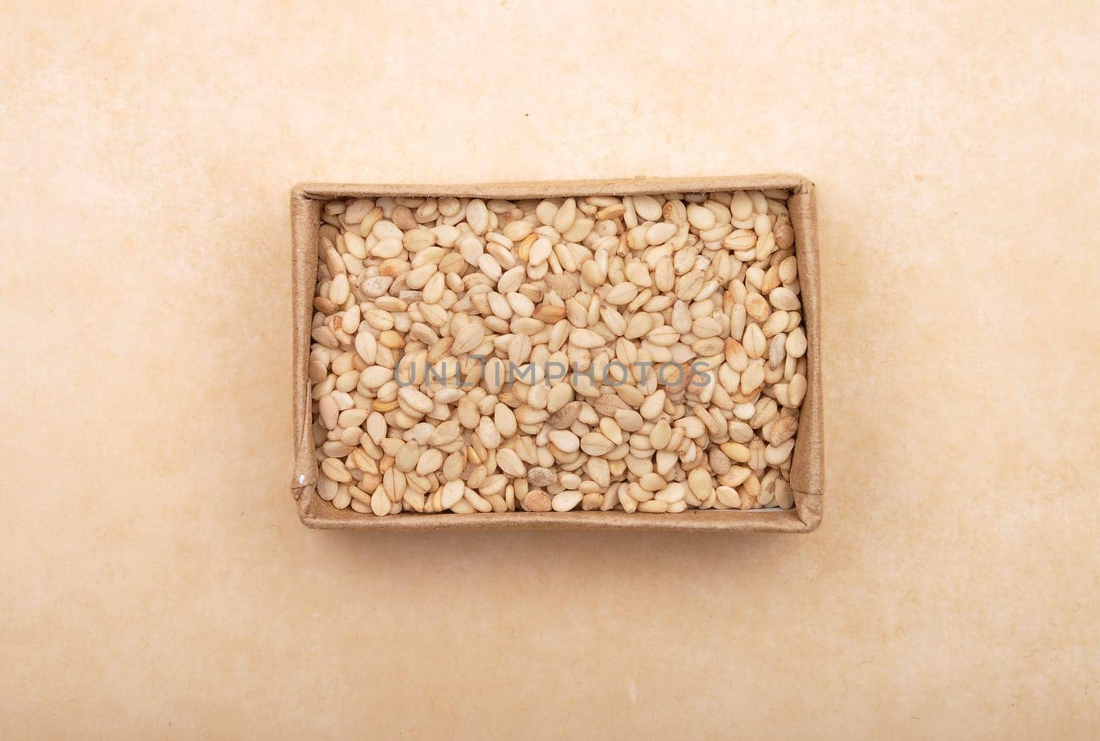 Sesame in small carton on brown background