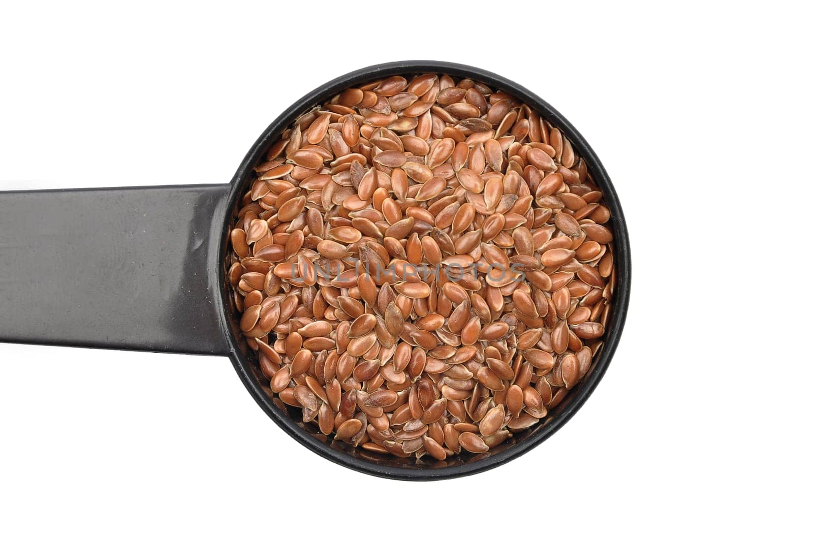 Linseed in measuring spoon on white background