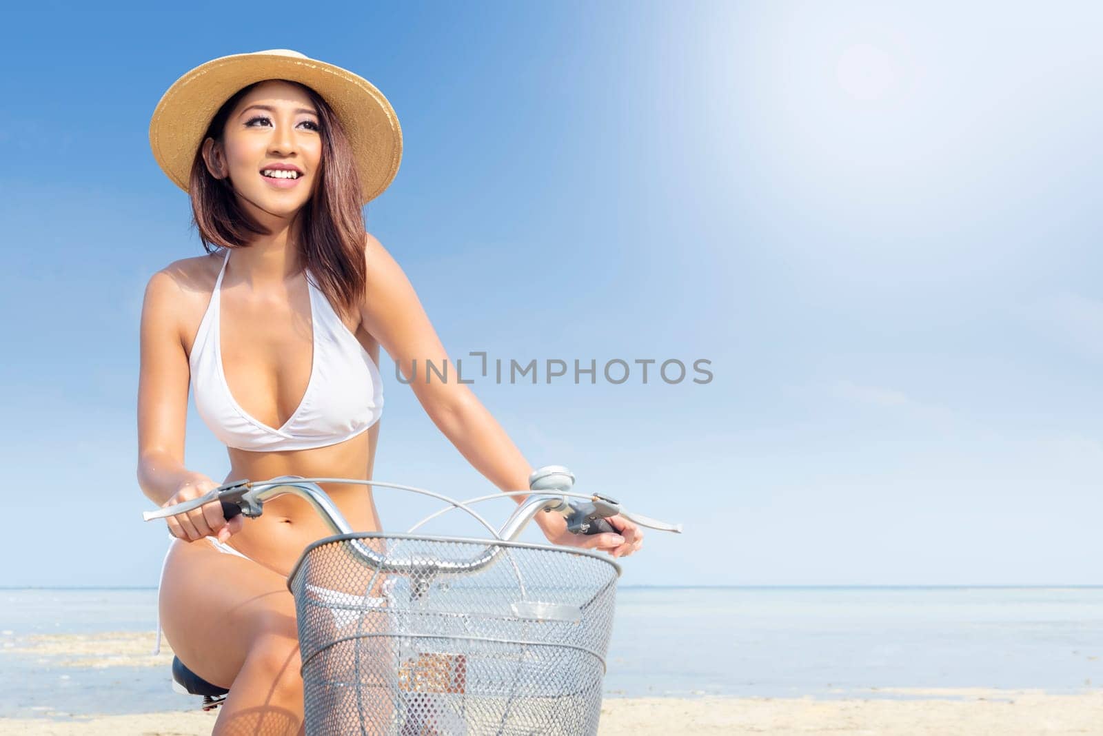 Close up view of asian sexy girl with hat and bikini riding bicycle on the beach. Summer vacation