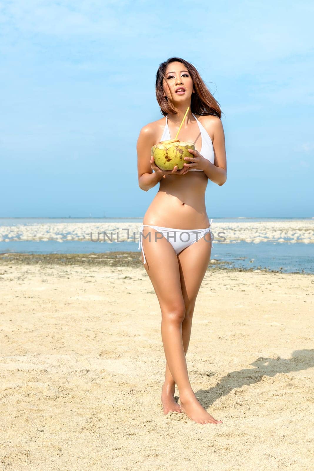 Asian sexy girl in bikini holding coconuts on the beach. Summer vacation