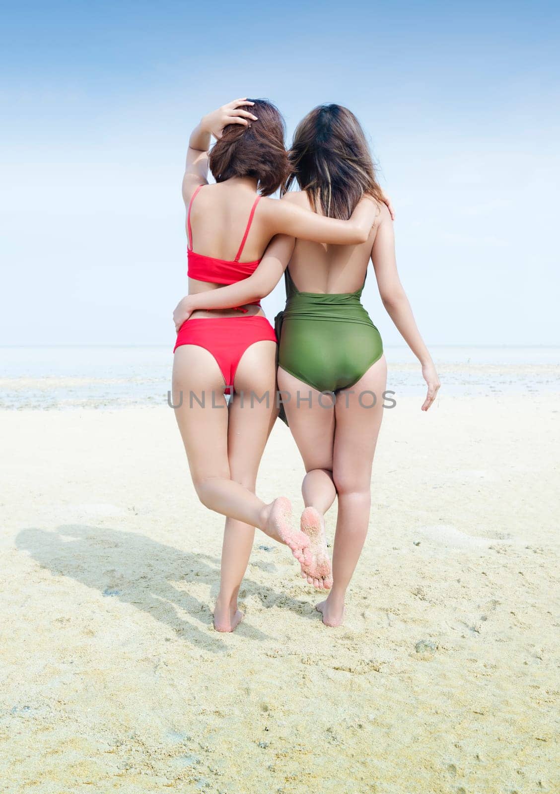 Rear view of two asian sexy girl in bikini and swimsuit on the beach. Summer vacation