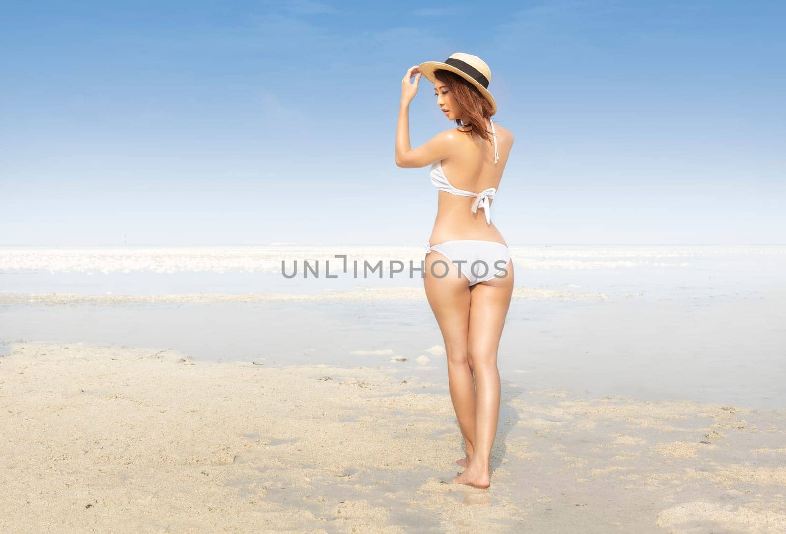 Rear view of asian sexy girl with hat and bikini on the beach. Summer vacation
