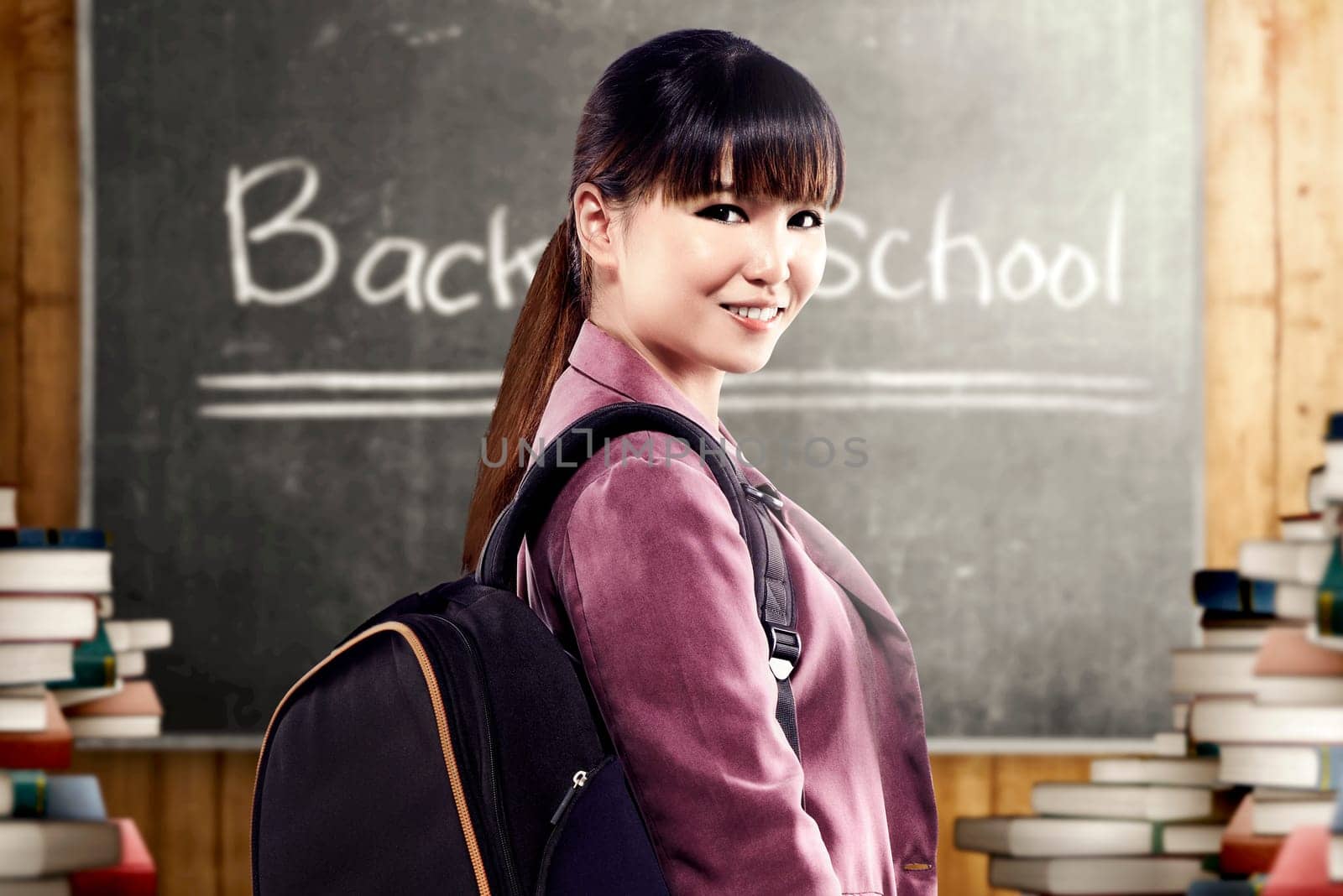 Asian student woman with backpack standing and look back in the classroom with piles of books and blackboard background. Back to School concept