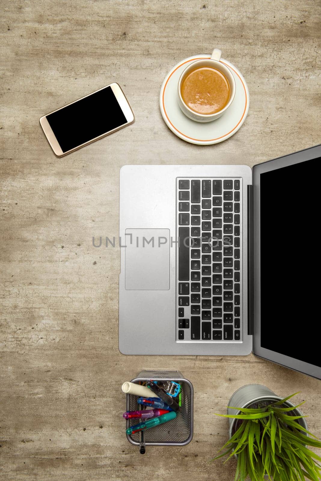 Top view of business desk with laptop, coffee, potted plant, mobile phone and business accessories on the office