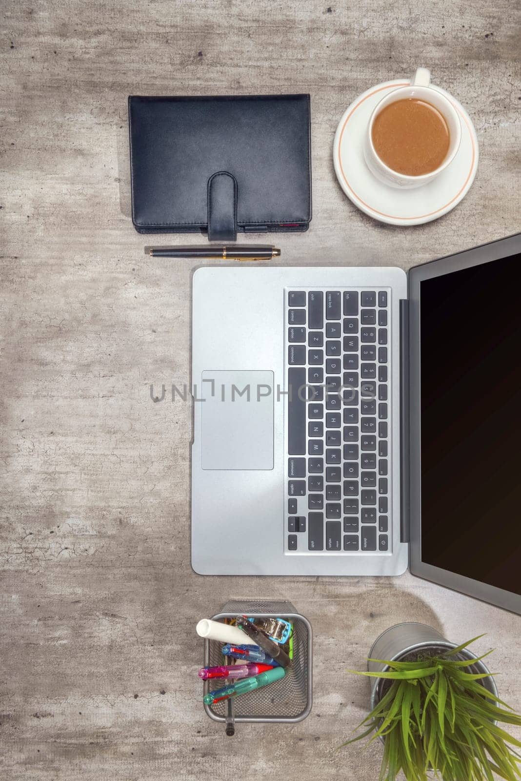 Top view of business desk with laptop, coffee, potted plant, notebook and business accessories on the office