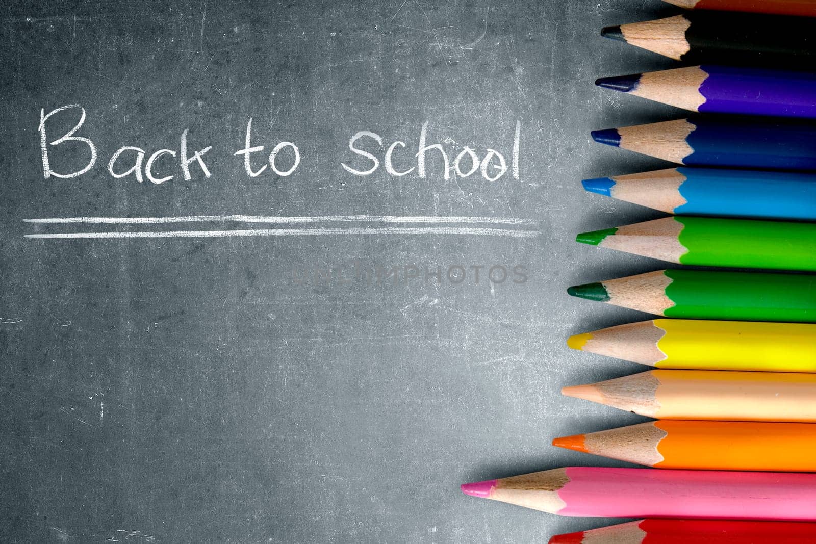 Row of colorful stationery of pencils for drawing on blackboard with Back to School message. Back to School concept