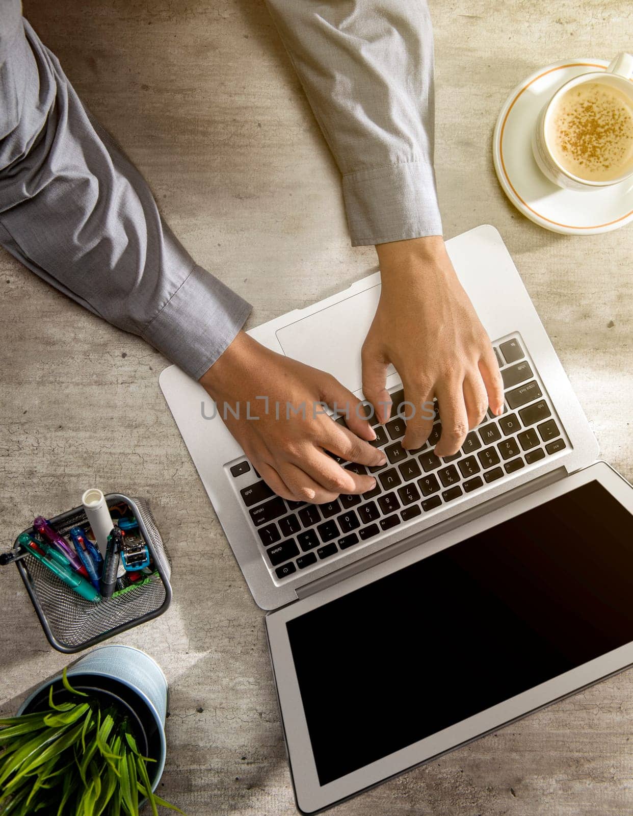 Top view of businessman working using laptop with coffee, potted plant and business accessories on the desk