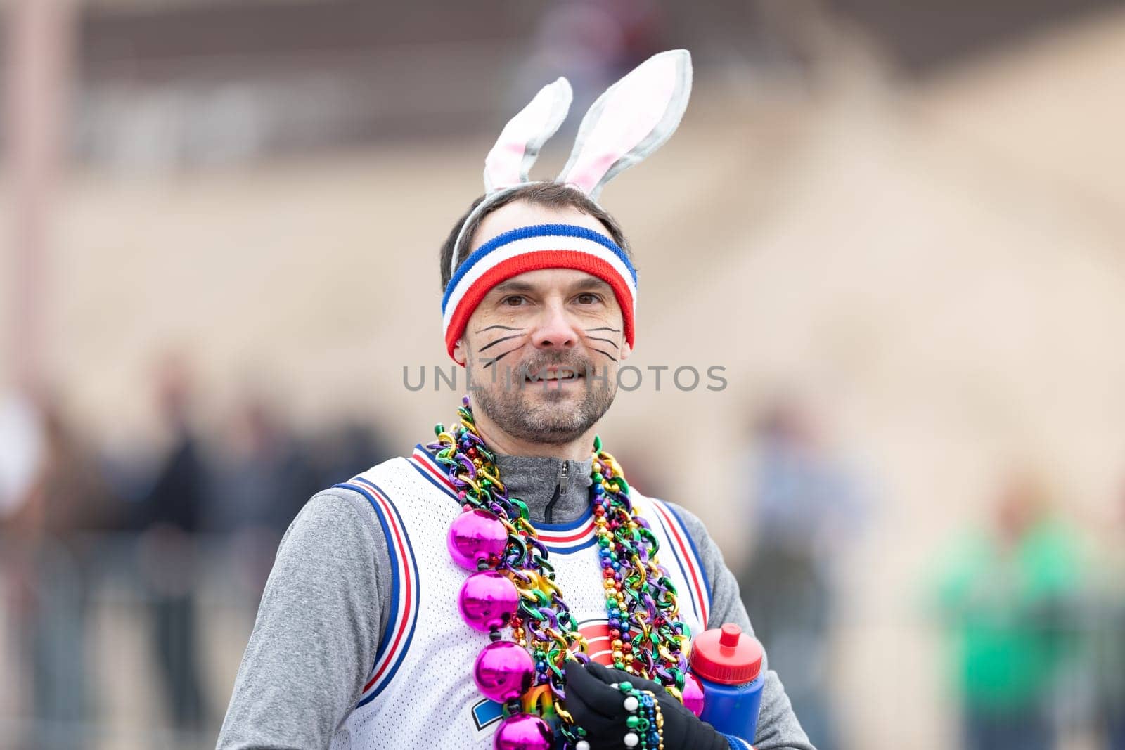 St. Louis, Missouri, USA - March 2, 2019: Bud Light Grand Parade, man skating and wearing a bunny hat, and beads, looking at the camera