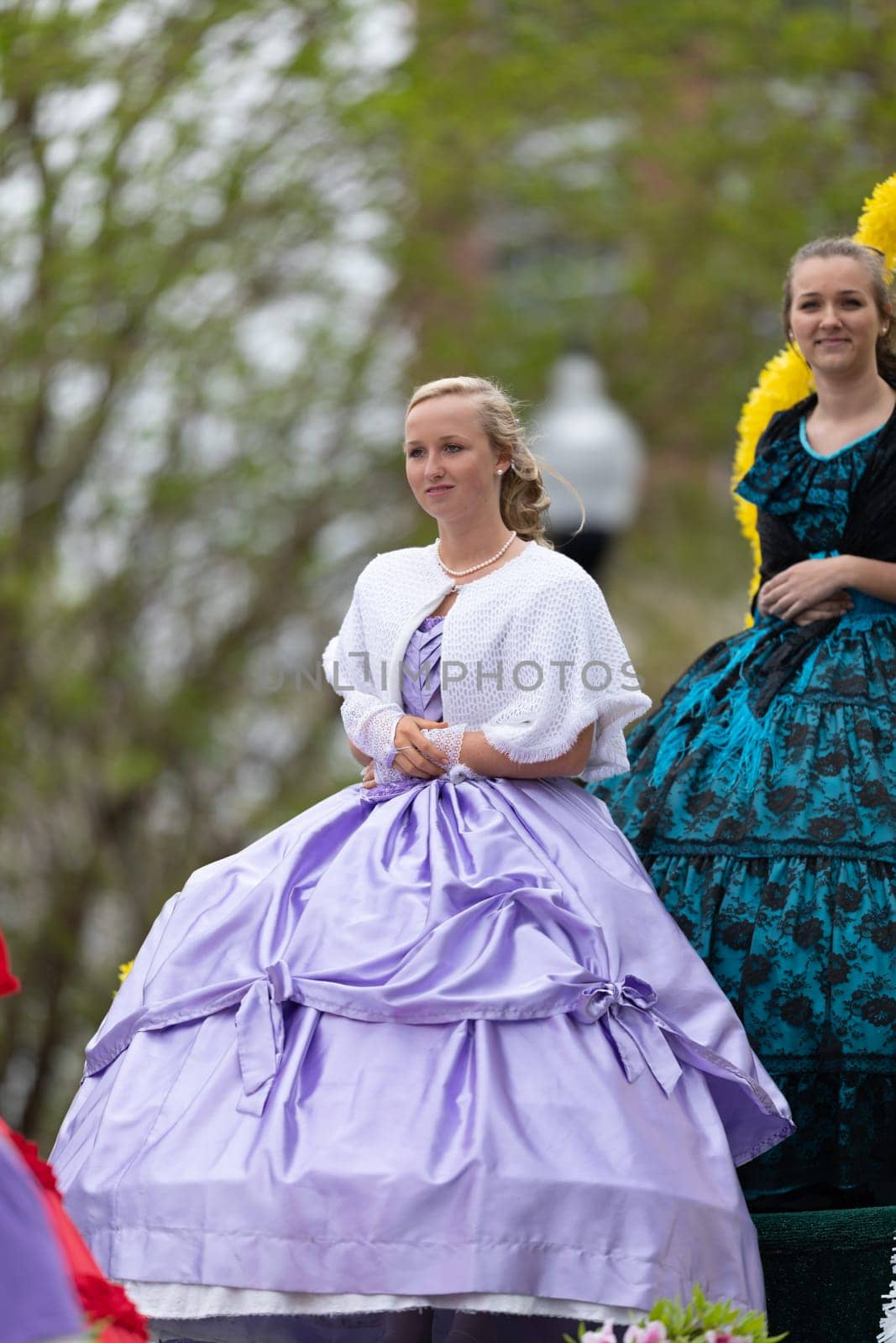 Wilmington, North Carolina, USA - April 6, 2019: The North Carolina.Azalea Festival, Young woman riding a float wearing a traditional dress at the parade