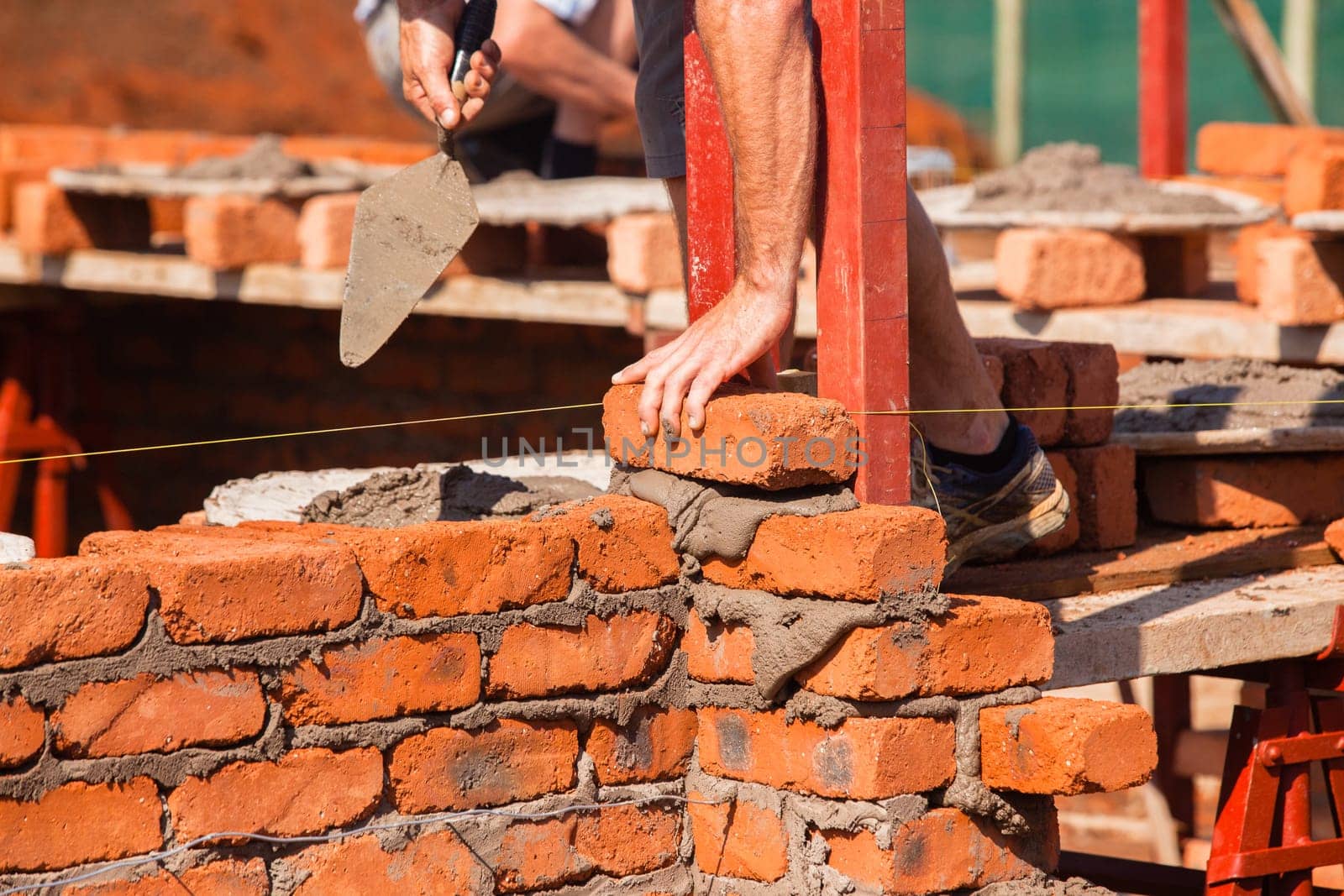 Building construction artisan hands tool laying bricks closeup cement wire wall construction