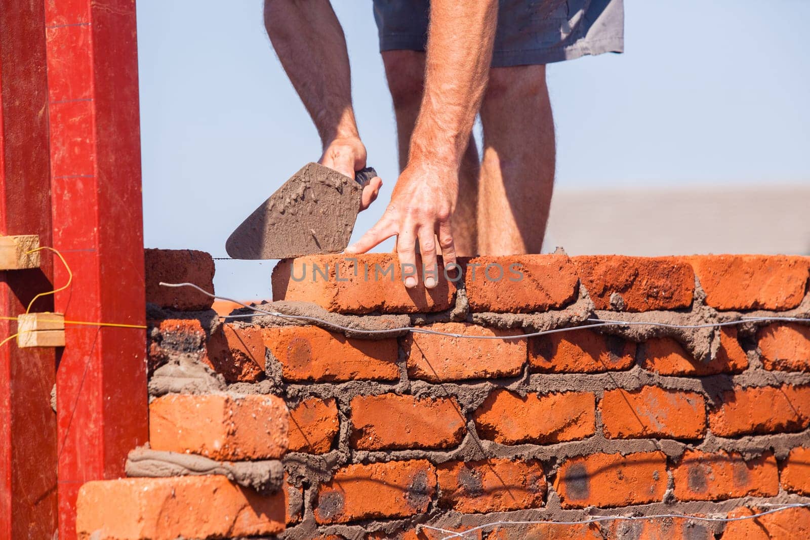 Building construction artisan hands tool laying bricks closeup cement wire wall construction