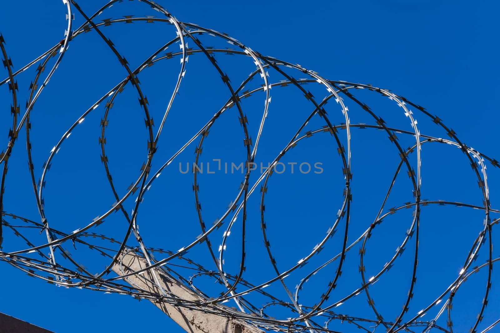 Razor steel wire security protection boundary fencing closeup section in blue sky.