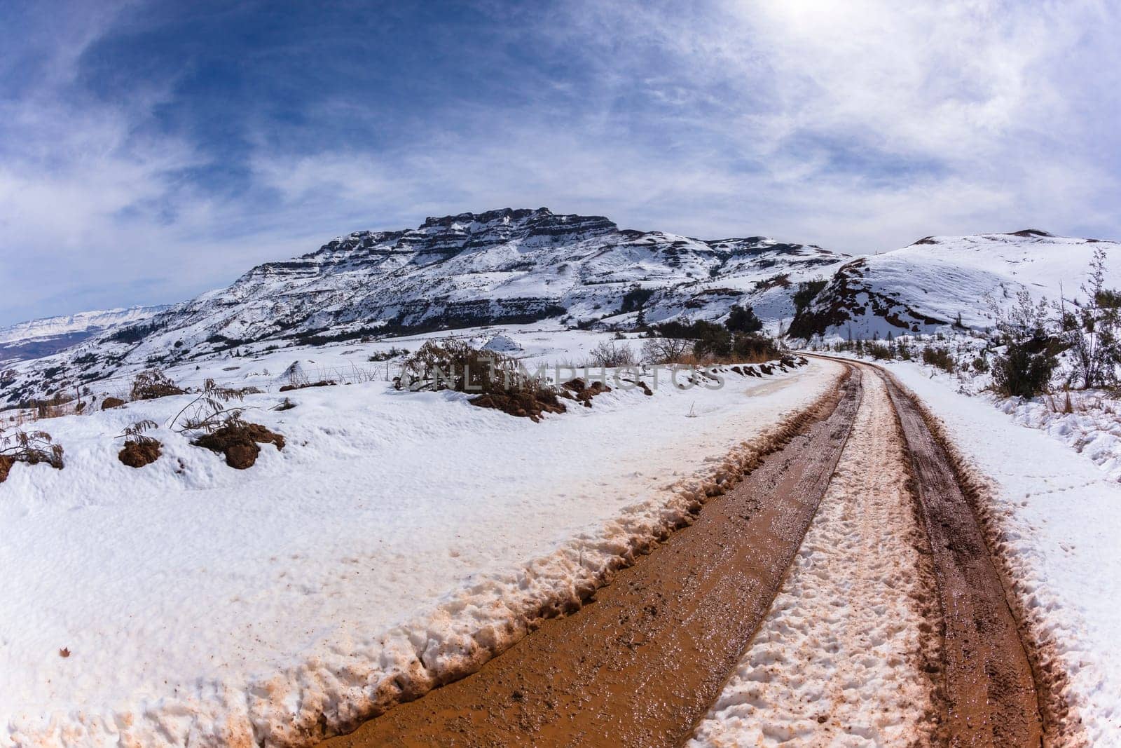 Mountains Snow dirt road vehicle tracks towards hilltop in winter landscape