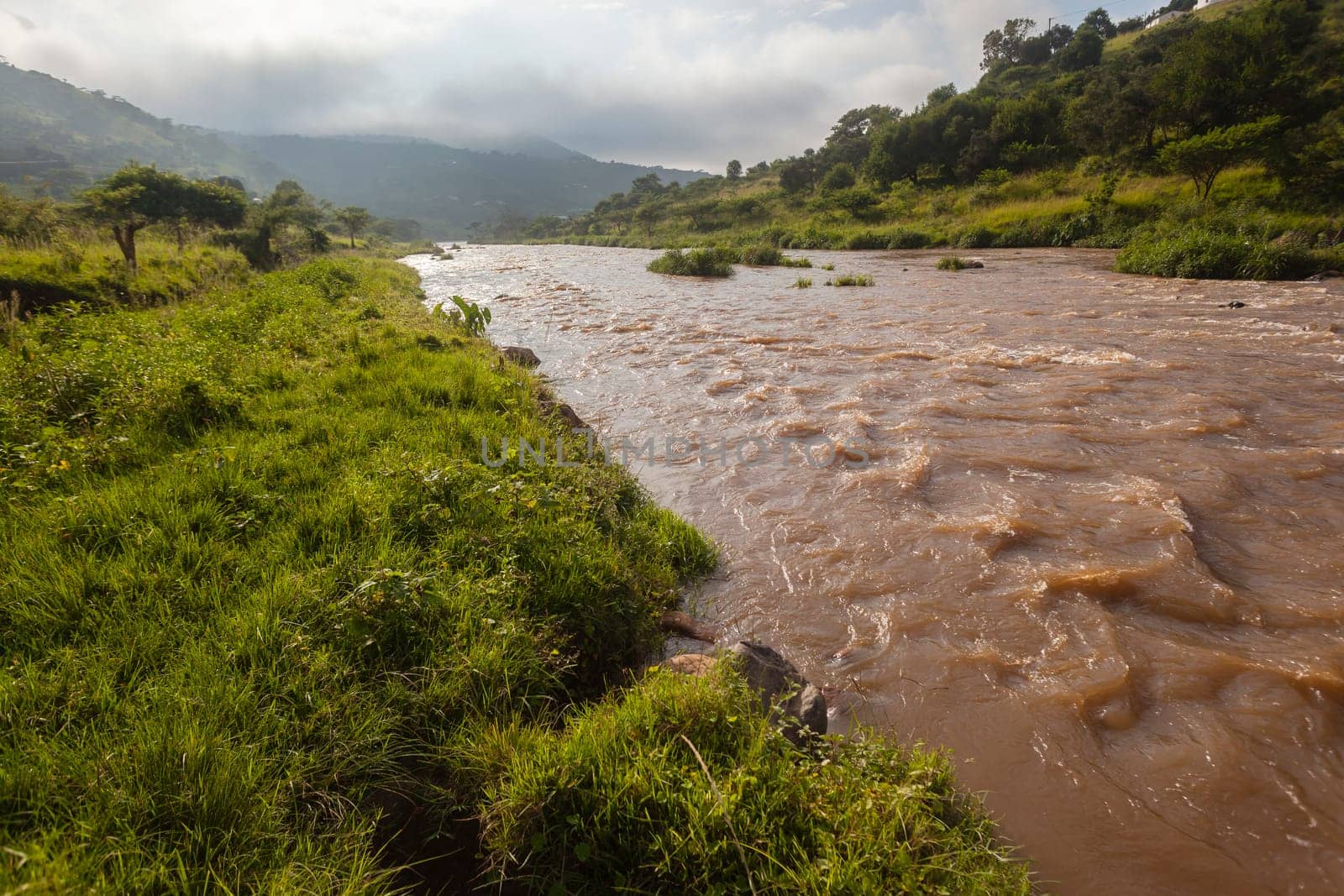 River water flowing closeup photo on bank through rural valley  landscape