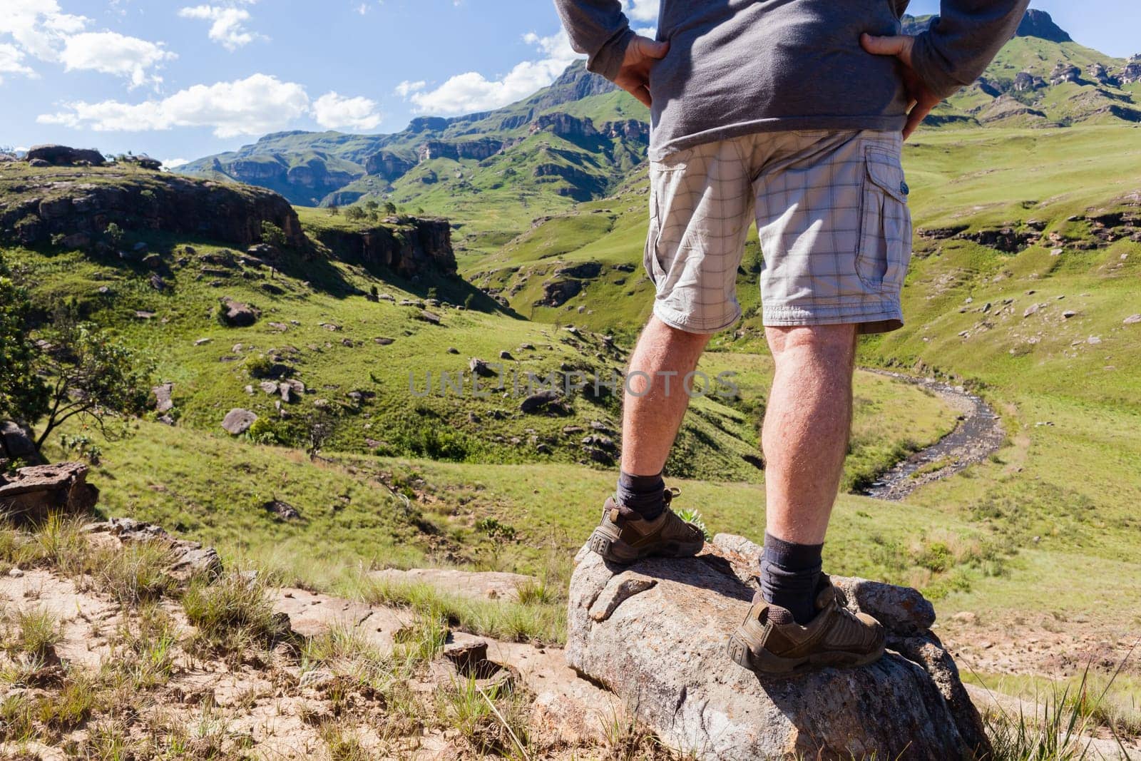 Hiker closeup rear from legs of adventurer looking over mountains  valley river on Sani-Pass landscape summer afternoon.