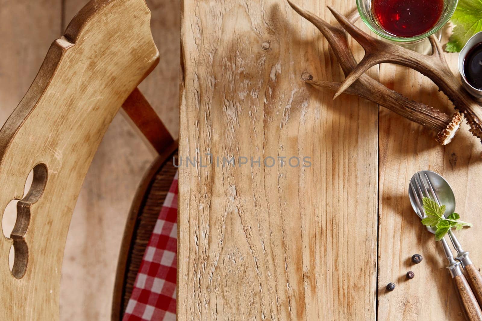 Autumn hunting table with deer antlers, glass of red wine, green leaves and fresh herbs on utensils with copy space viewed from above