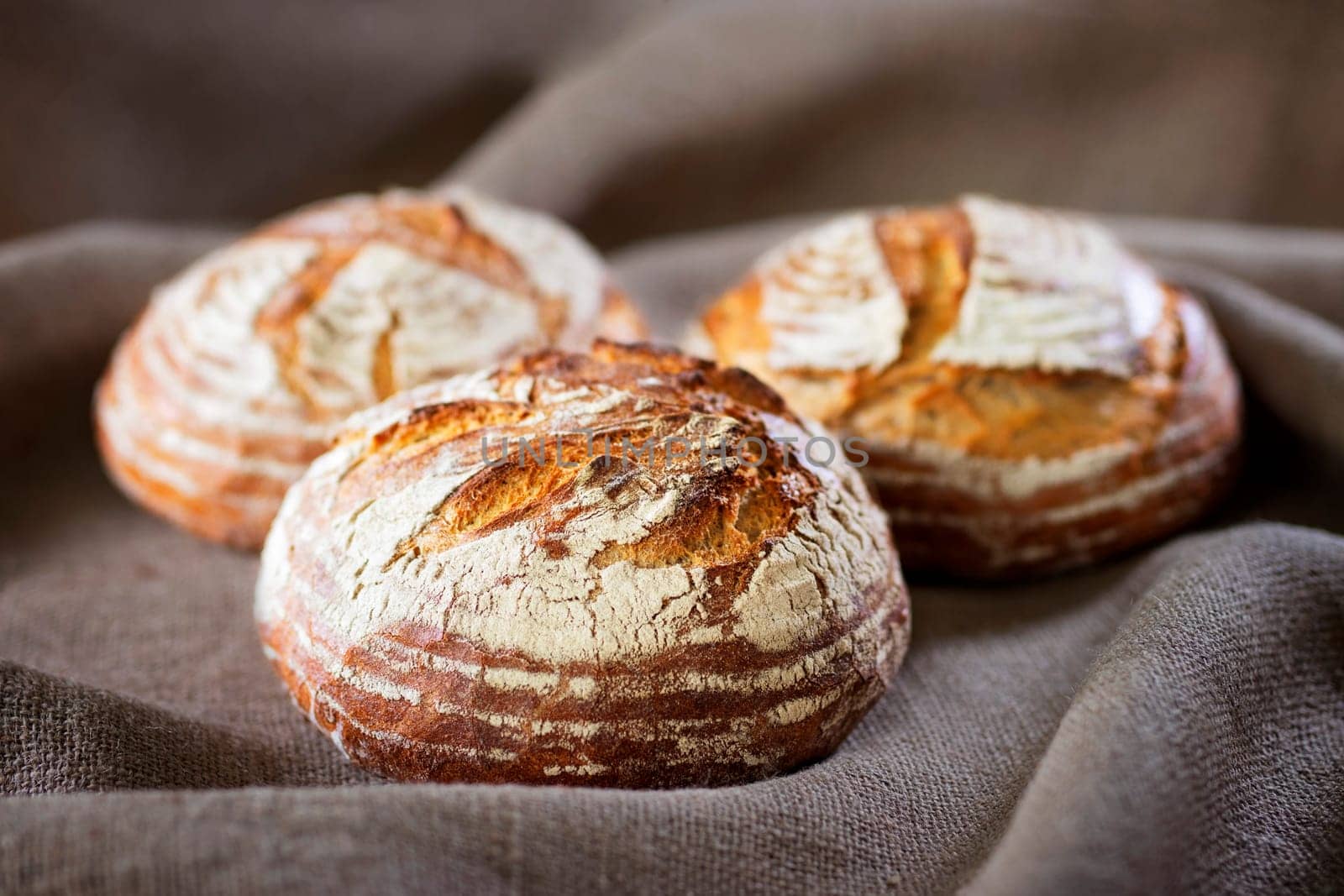 Three industrial round rye bread on burlap canvas