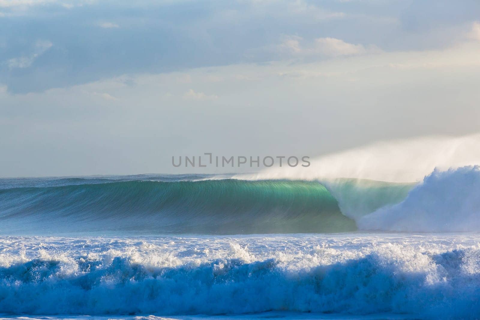 Ocean waves crashing water power towards beach from weather storms.