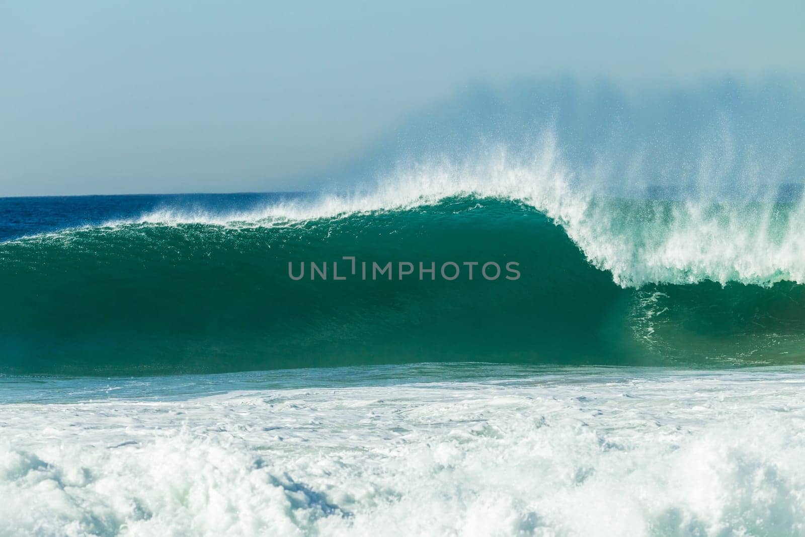 Ocean large waves crashing water power towards beach from weather storms.