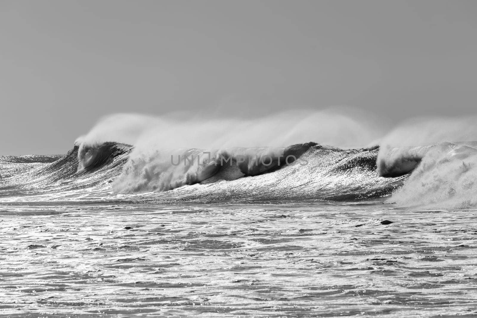 Ocean large waves crashing water power towards beach from weather storms.