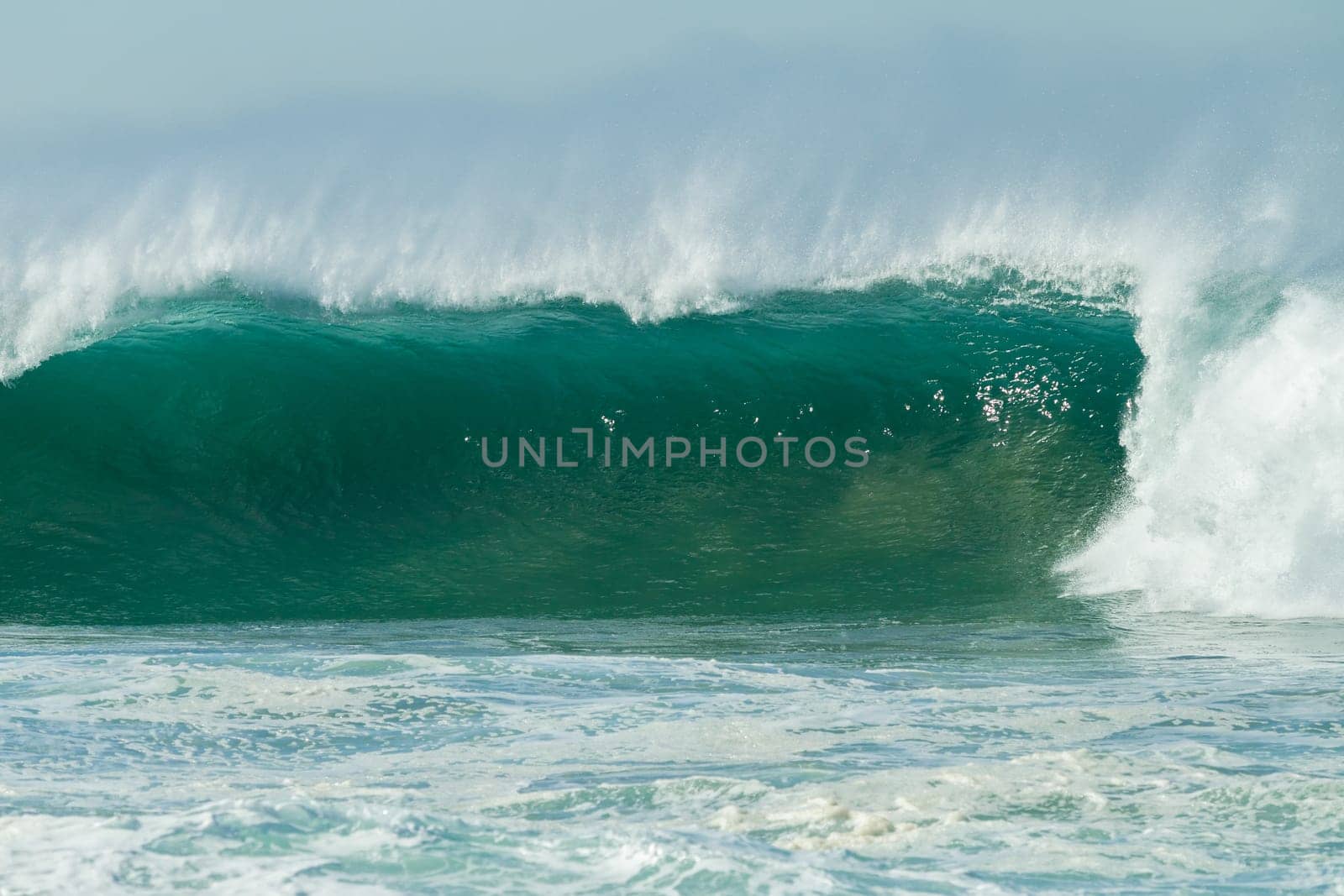 Ocean large waves crashing water power towards beach from weather storms.