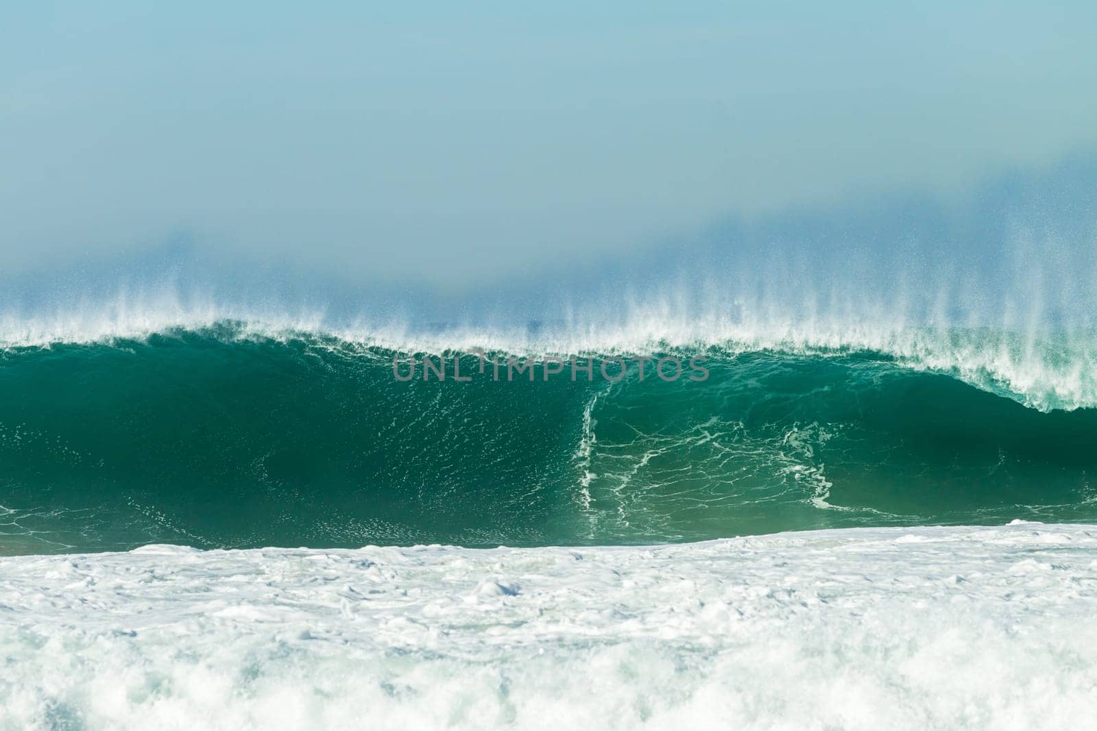 Ocean large waves crashing water power towards beach from weather storms.
