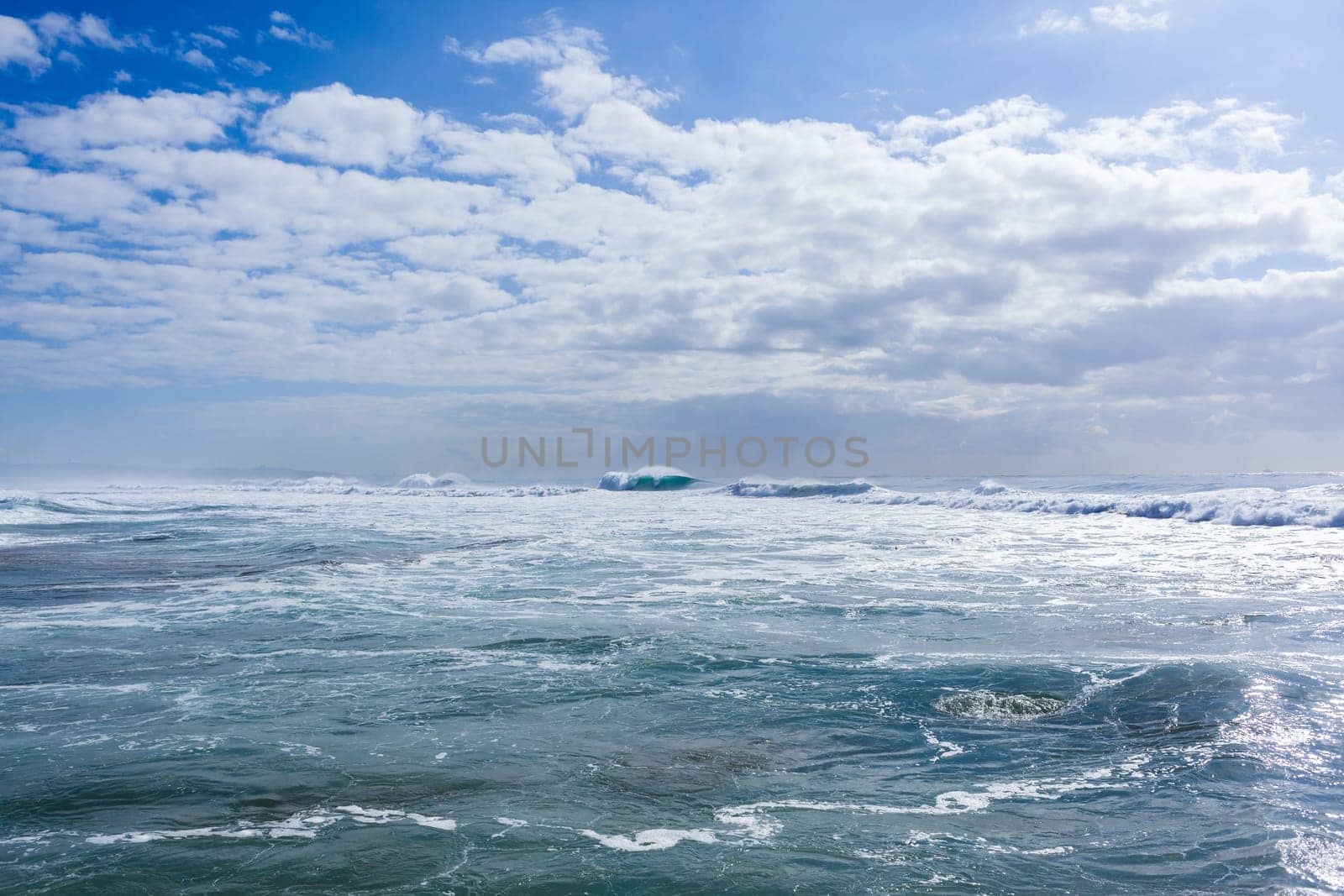 Ocean large waves crashing water power towards beach from weather storms.
