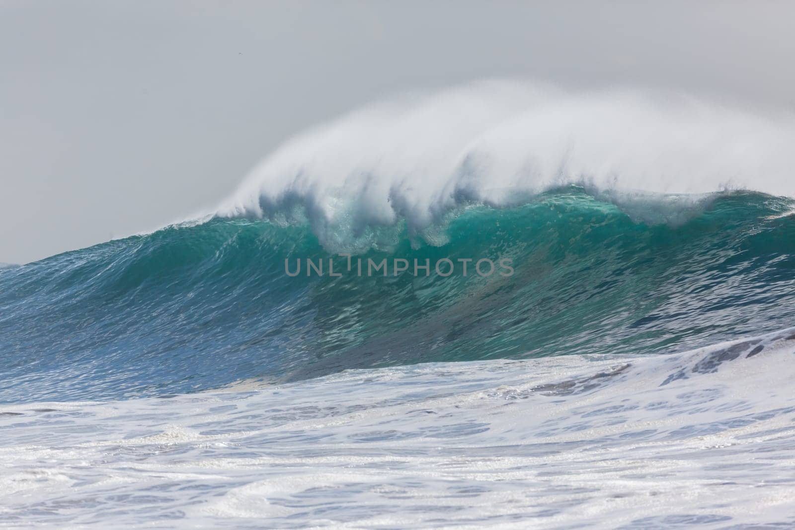 Ocean large waves crashing water power towards beach from weather storms.