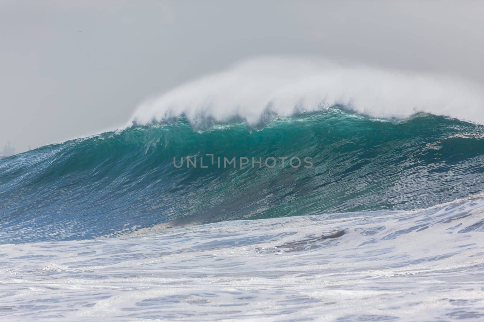 Ocean large waves crashing water power towards beach from weather storms.