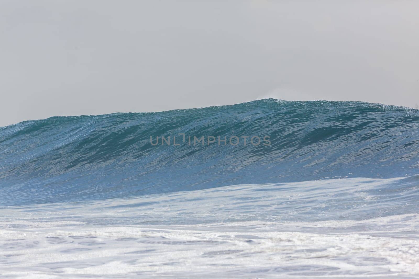 Ocean large waves crashing water power towards beach from weather storms.