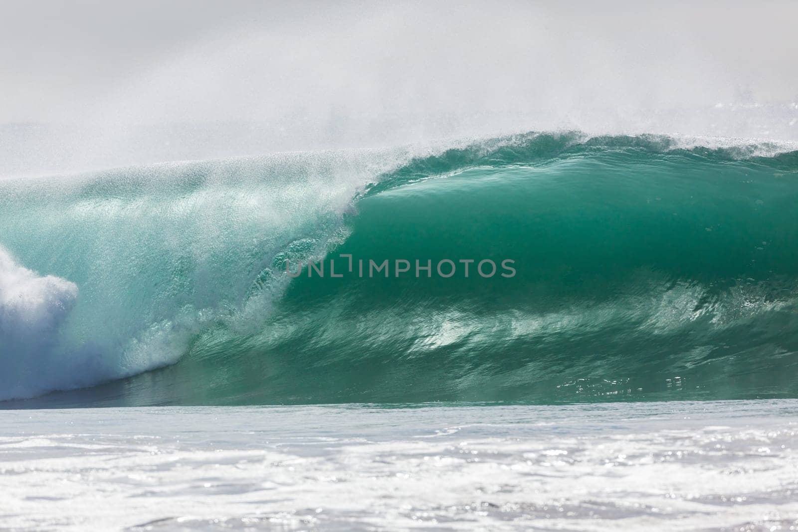 Ocean large waves crashing water power towards beach from weather storms.