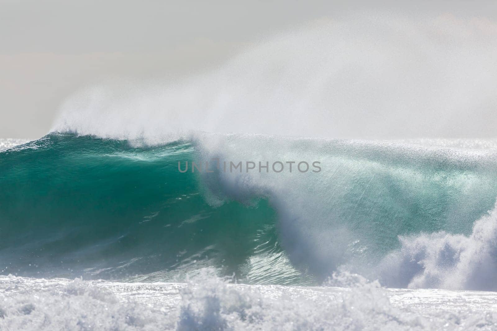 Ocean large waves crashing water power towards beach from weather storms.